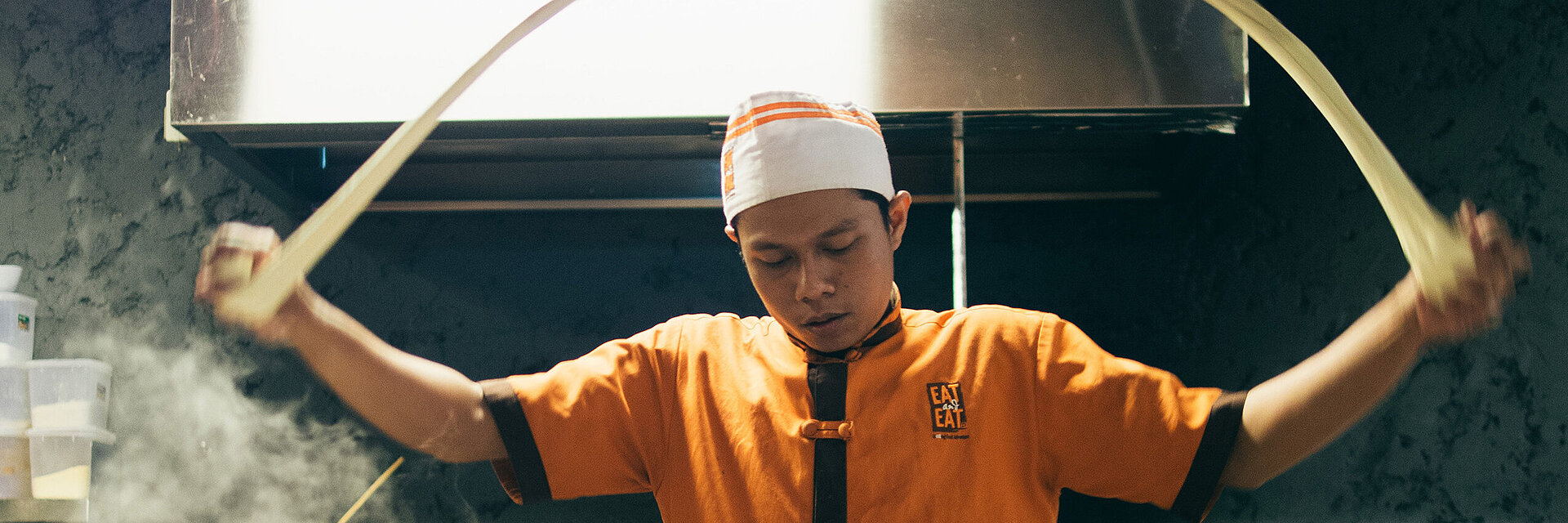 [Translate to Vietnamesisch:] Asian cook with embroidered working shirt