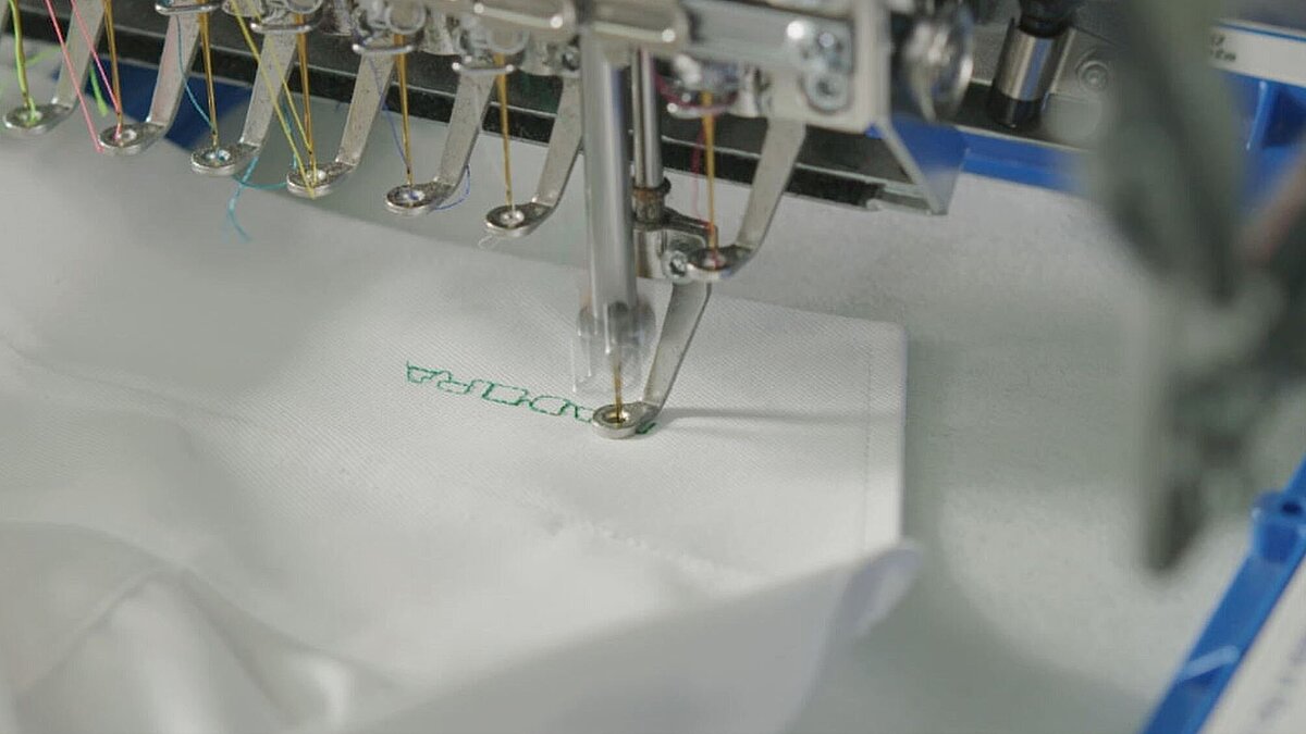 [Translate to Hongkong (Englisch):] White shirt collar being embroidered using Stick-On adhesive backing