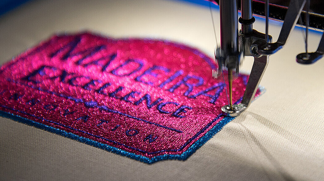 [Translate to Hongkong (Englisch):] Shiny pink metallic thread emboirdery badge on a machine 