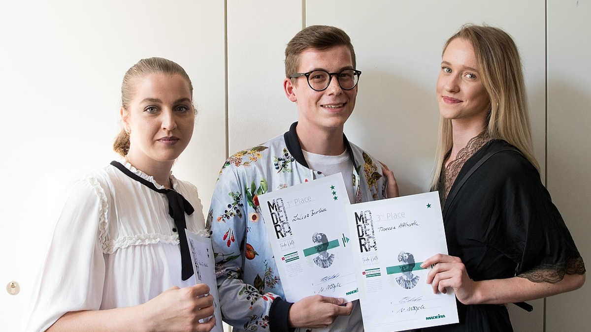 The winning picture shows the 3 winners of the competition. They hold up their certificate with satisfaction.